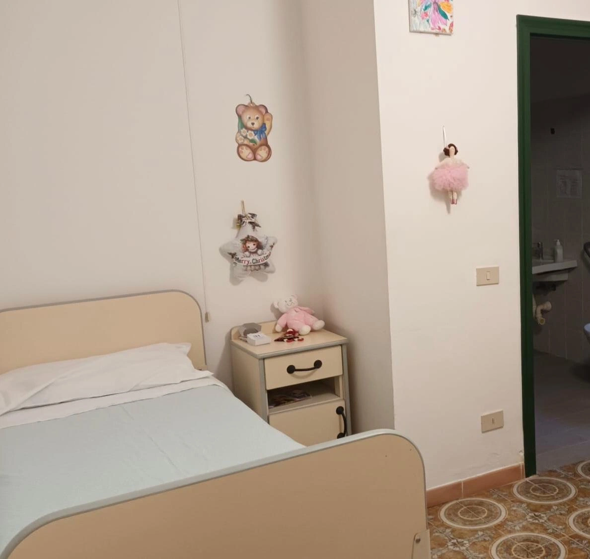 Foto di una stanza da letto con in primo piano il letto con alla sua sinistra un comodino